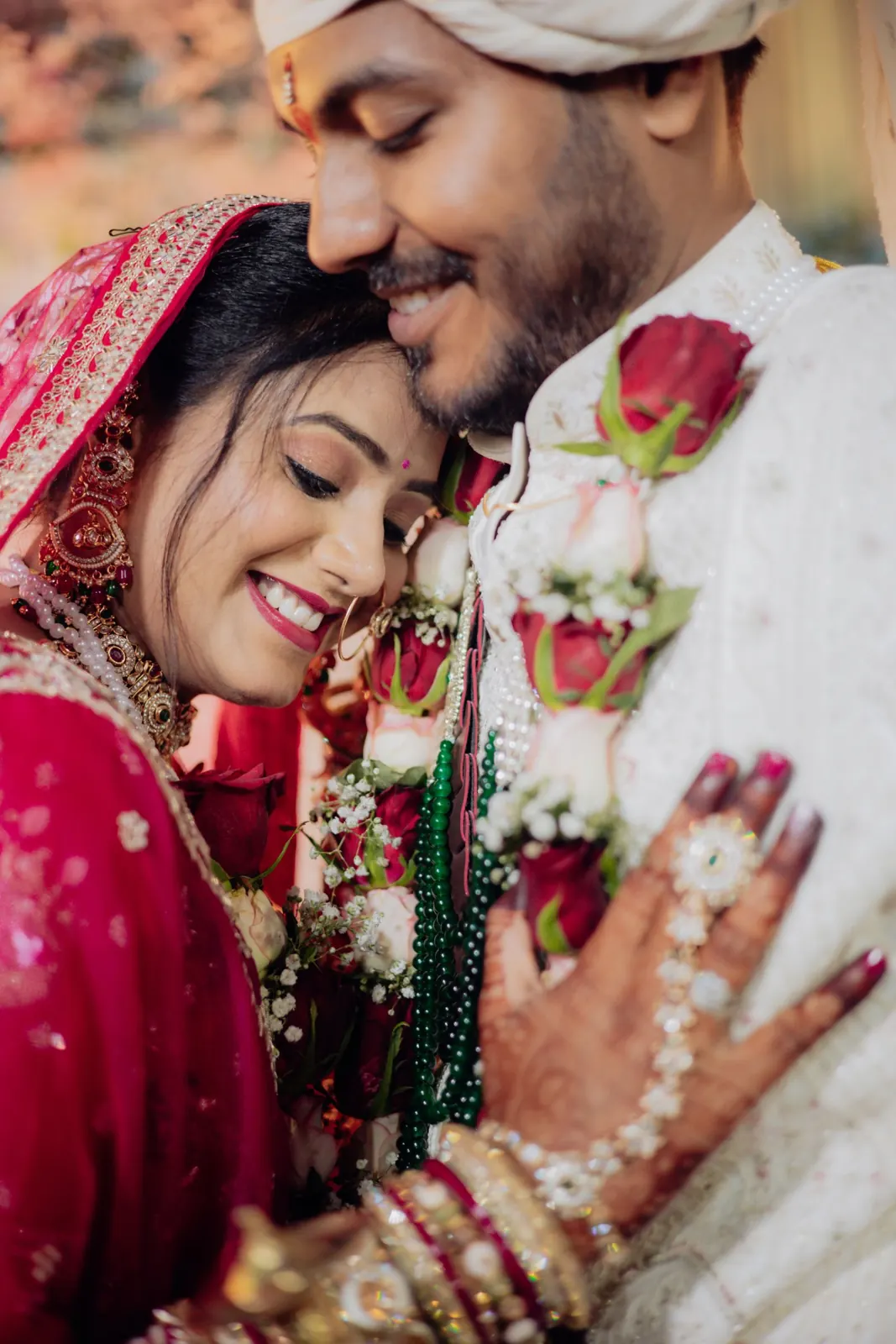 A bride and groom in traditional attire, foreheads touching